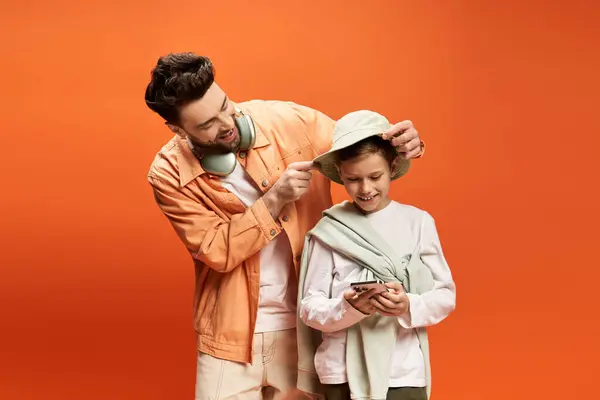 A father lovingly adjusts his sons hat while they share smiles and enjoy their time together. — Stock Photo
