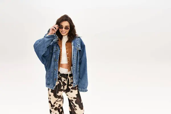 A confident young woman in a trendy outfit smiles, striking a pose with cow print pants. — Stock Photo