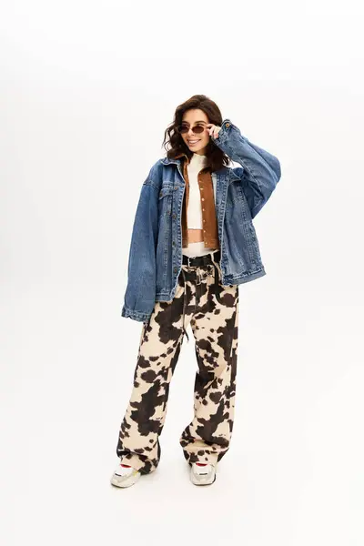 Young woman flaunts a trendy outfit featuring cow print pants against a minimalist backdrop. — Stock Photo