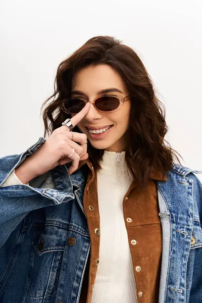 A young woman poses confidently sunglasses, exuding fashion flair in studio. — Stock Photo