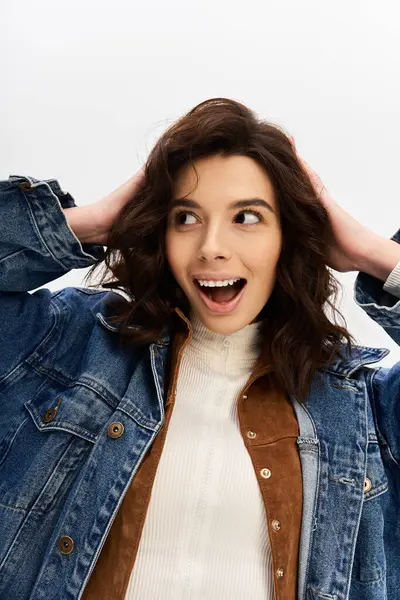 A young woman excitedly poses in a trendy outfit featuring cow print pants against a grey backdrop. — Stock Photo