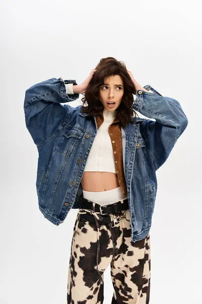 A young woman displays her fashionable outfit featuring cow print pants in a studio environment. — Stock Photo