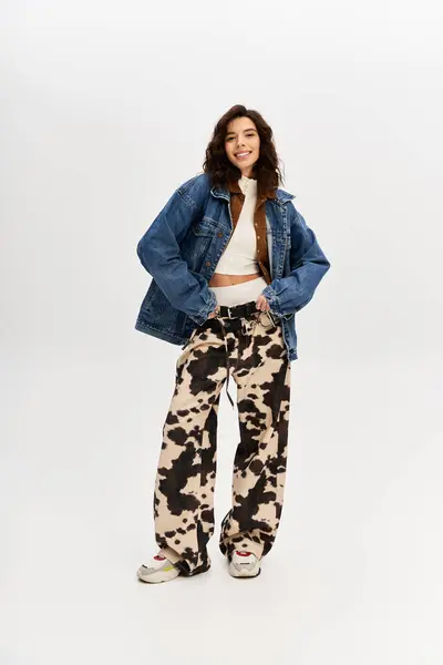 A stylish young woman confidently poses in trendy cow print pants. — Stock Photo