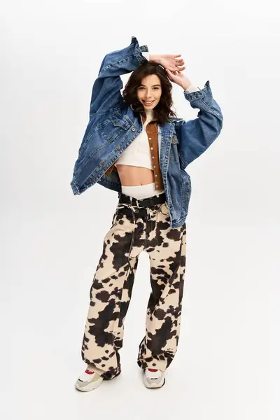 A young woman confidently poses in a trendy outfit featuring cow print pants while smiling. — Stock Photo
