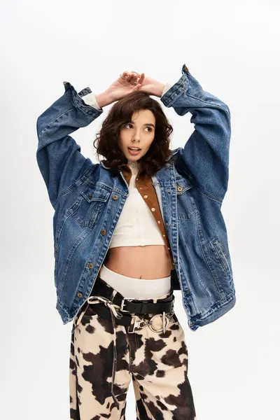 Young woman in trendy outfit poses confidently with cow print pants and denim jacket. — Stock Photo
