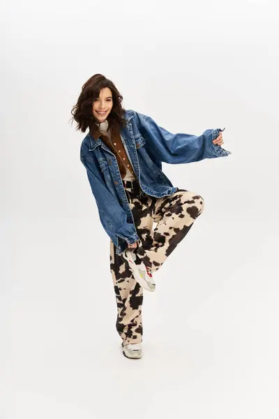 A confident young woman poses in a trendy cow print outfit against a grey backdrop. — Stock Photo