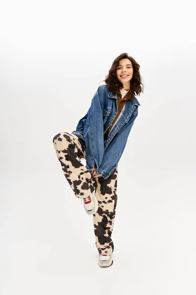 Young woman in a trendy outfit, featuring cow print pants, poses playfully in a studio setting. — Stock Photo