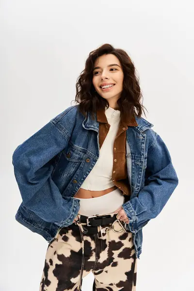 A young woman confidently poses in a chic cow print ensemble against a grey backdrop. — Stock Photo