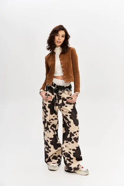 Young woman in a fashionable outfit poses confidently against a sleek grey background. — Stock Photo