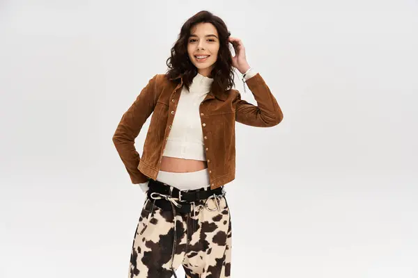 A young woman poses confidently in stylish cow print pants and a chic jacket, exuding fashion. — Stock Photo