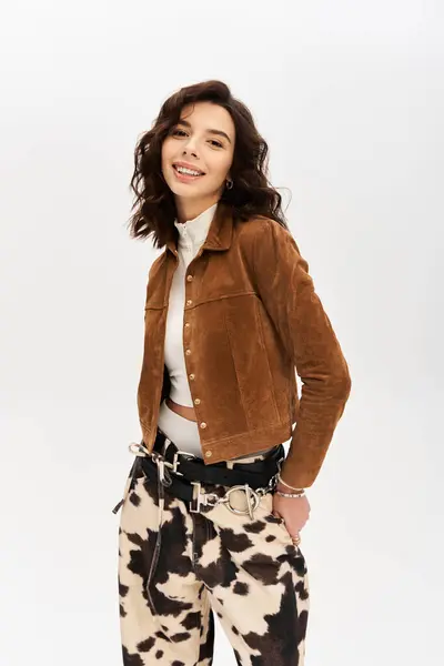Young woman showcases her trendy outfit featuring cow print pants against a grey studio backdrop. — Stock Photo