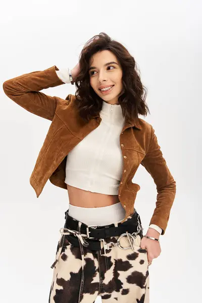 A stylish young woman poses confidently in cow print pants against a grey background. — Stock Photo