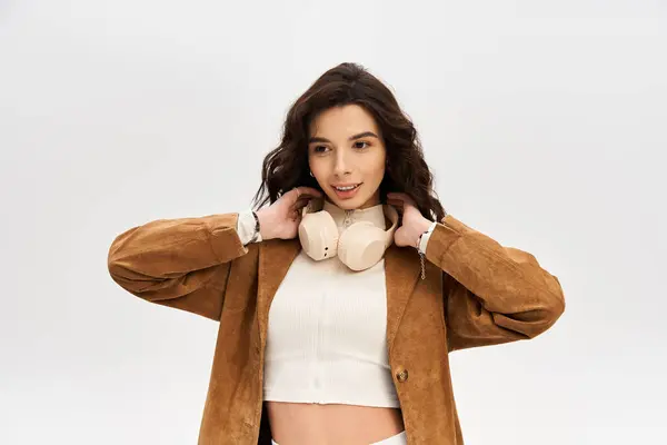 A young woman standing with headphones while posing in a studio setting. — Stock Photo
