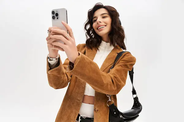 A young woman showcases her trendy cow print outfit while taking a selfie in a studio. — Stock Photo