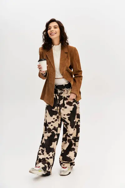 A young, fashionable woman poses confidently in a trendy outfit with unique cow print pants. — Stock Photo