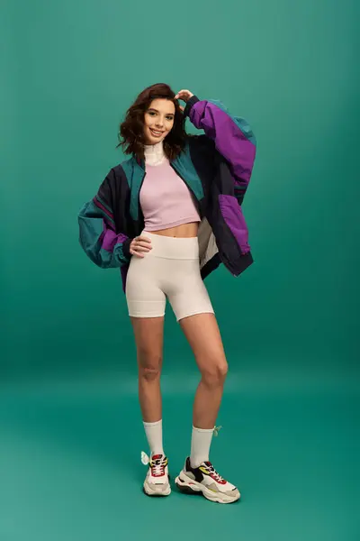 A young woman confidently poses in a vibrant sporty outfit, exuding modern fashion vibes. — Stock Photo