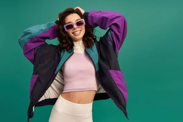 A stylish young woman shows off her sporty outfit while posing playfully in studio lights. — Stock Photo