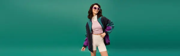 Stylish woman stands confidently in a sporty outfit against a bright turquoise background, banner — Stock Photo