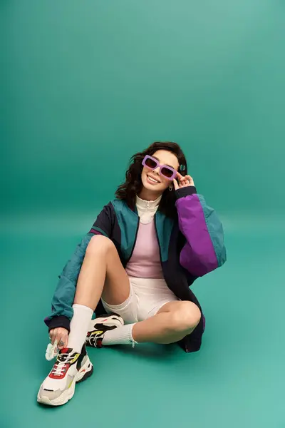 A young woman poses playfully in a trendy sporty outfit, enjoying the vibrant backdrop. — Stock Photo