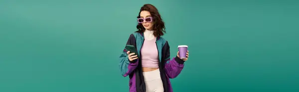 A trendy woman stands confidently against a turquoise backdrop holding coffee and phone, banner — Stock Photo