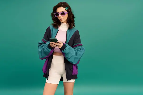 Young trendy woman sporting a stylish windbreaker and shorts engages with her smartphone. — Stock Photo