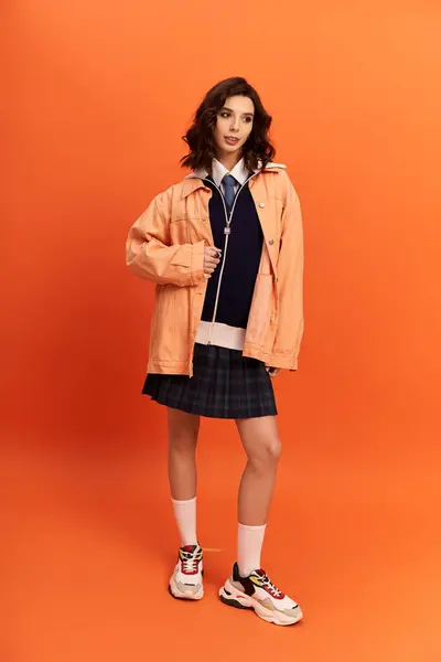 Young woman showcases her fashionable attire in a studio setting filled with warmth and creativity. — Stock Photo