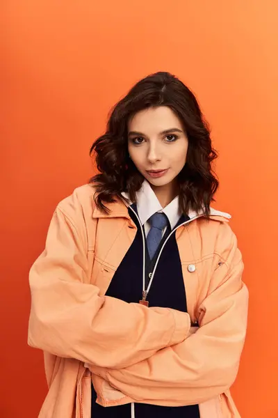 Stylish young woman poses confidently in a chic outfit on a vibrant orange background. — Stock Photo