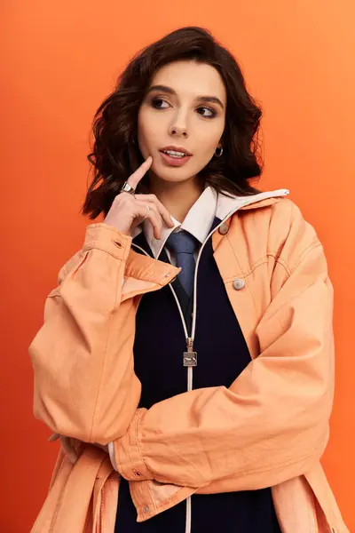 A poised young woman showcases a trendy outfit featuring jacket in a bright studio. — Stock Photo
