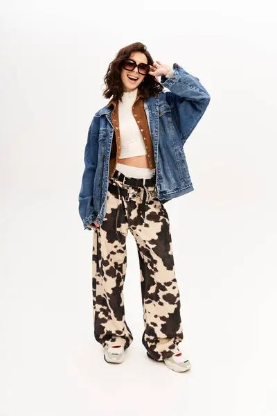 Young woman poses confidently in a trendy cow print outfit against a grey backdrop. — Stock Photo