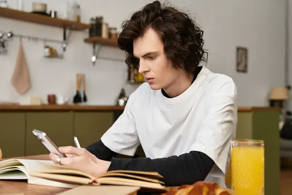 Cozy young man relaxed at home, engaged with his smartphone and a glass of juice nearby. — Stock Photo