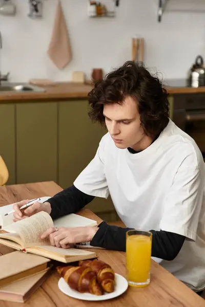 Bright and inviting space where a young man reads a book, savoring fresh croissants and juice — Stock Photo