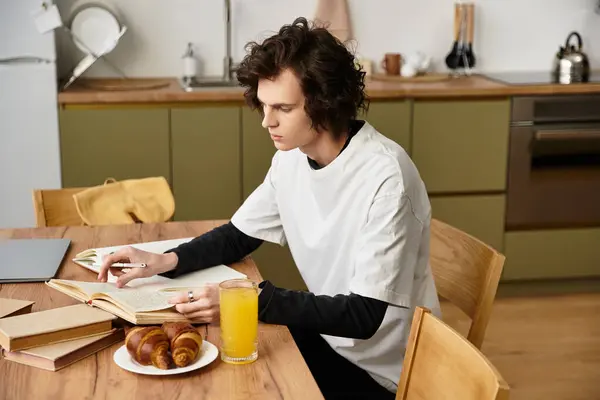 Young man enjoys his breakfast while reading at a stylish kitchen table, exuding comfort and focus. — Stockfoto