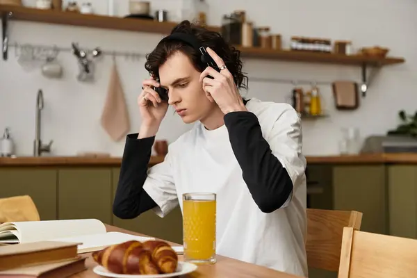 A young man relaxes at home in comfortable clothing, enjoying breakfast and music. — Stock Photo