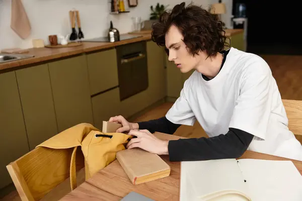 In a cozy kitchen, a young man carefully sorts through a yellow bag. — Stockfoto