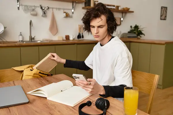 Cozy setting features a young man focused on his smartphone and notebook with casual style. — Stock Photo