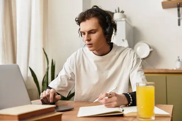 A young man sits at a wooden table focused on his laptop while sipping a refreshing drink. — Stock Photo