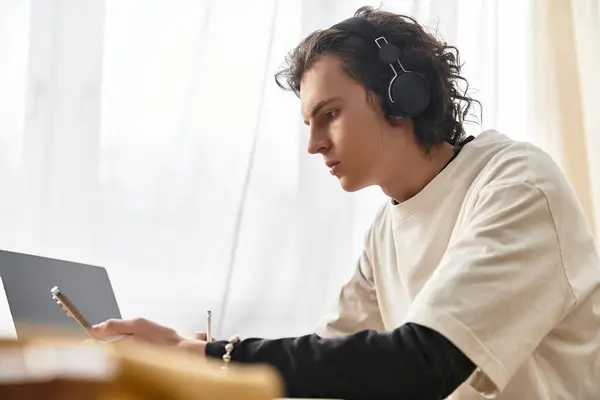 Focused young man works on his laptop at home, immersed in creativity while dressed comfortably. — Stock Photo