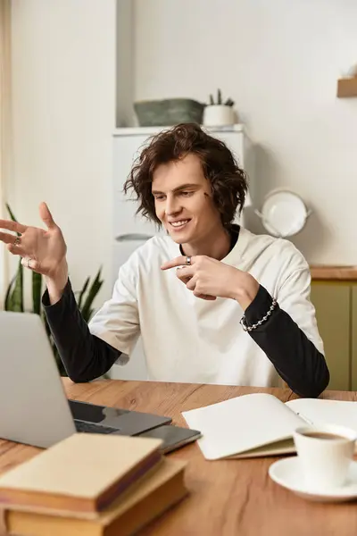 A cheerful young man engages eagerly online while sitting comfortably at home. - foto de stock
