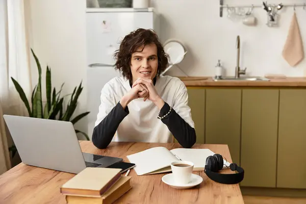 A young man sits comfortably at his wooden table in casual attire, focused on his creative work. — Stock Photo