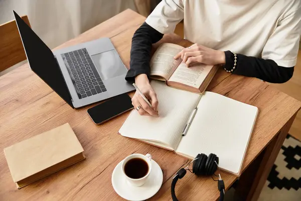 Young man in casual wear engages in a focused study session, taking notes while sipping coffee. — Stock Photo