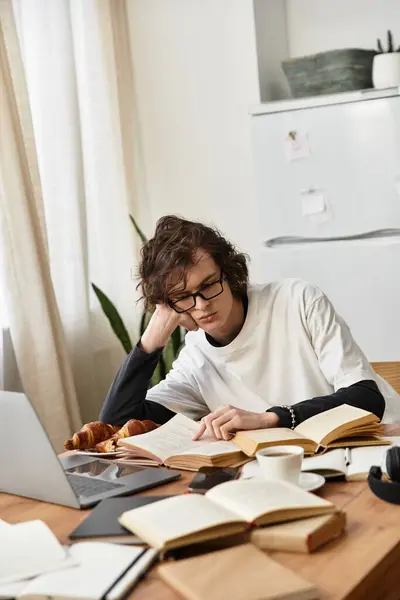 A cozy young man studies at home, surrounded by books and a laptop, exuding comfort. — Stock Photo