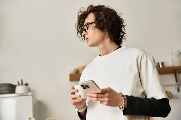 A young man in casual attire relaxes at home, focused on his smartphone in hand. — Stock Photo