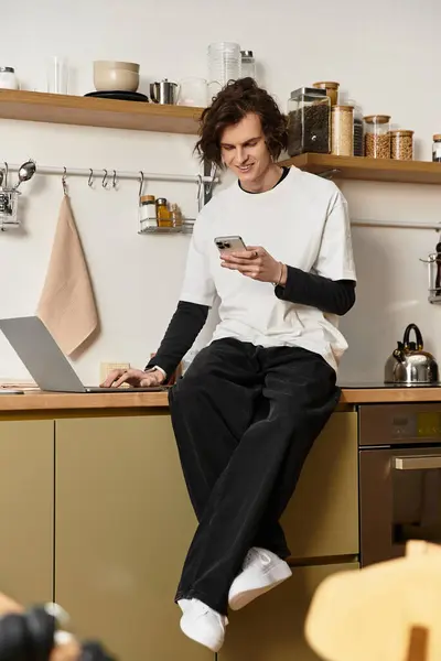 A young man lounges at home in comfortable clothes, enjoying a moment with his smartphone. — Foto stock