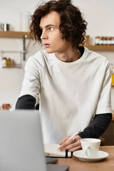 A young man relaxes at home, pen in hand, lost in thought while dressed comfortably. — Foto stock