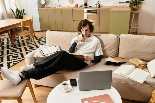 Young man dressed in casual clothes enjoys reading and reflecting at home in a warm atmosphere. — Fotografia de Stock
