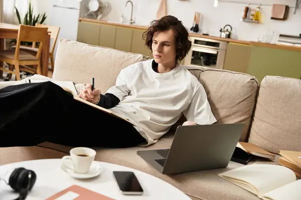 Relaxed young man at home captures inspiration while sitting on a comfy couch with a notebook. — Stock Photo