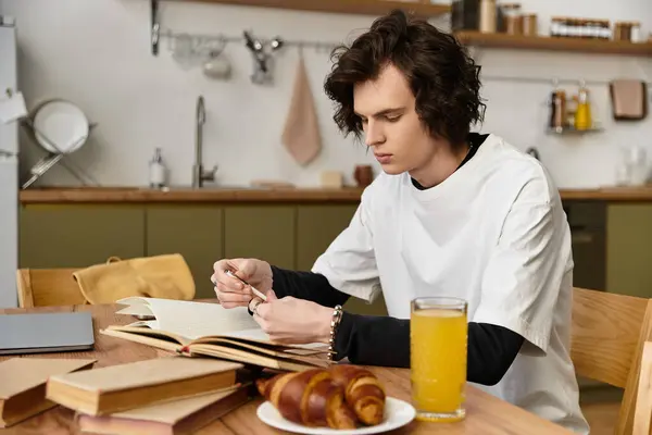 Cozy indoor atmosphere with a young man focused on reading at his kitchen table. — Photo de stock