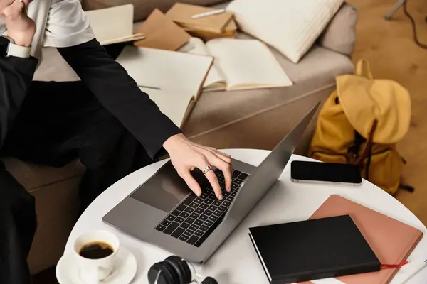 A young man works from home, surrounded by notepads and a warm drink, focused on tasks. — Stock Photo