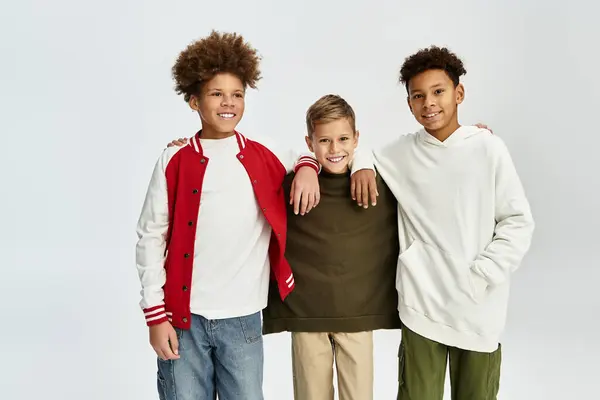 Three adorable boys display their strong bond while wearing trendy attire and smiling brightly. — Stock Photo