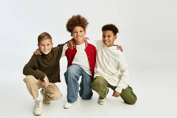 Three adorable boys dressed in stylish outfits express joy and camaraderie through playful poses. — Stock Photo